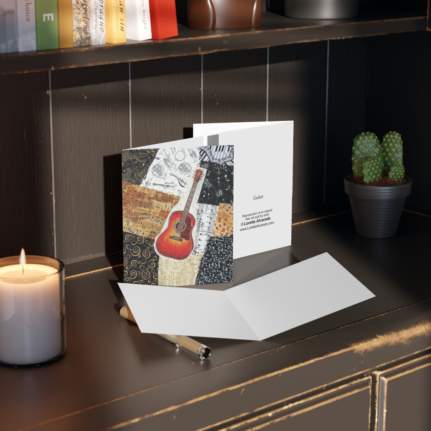 Greeting card with guitar design on a desk next to a candle and a plant