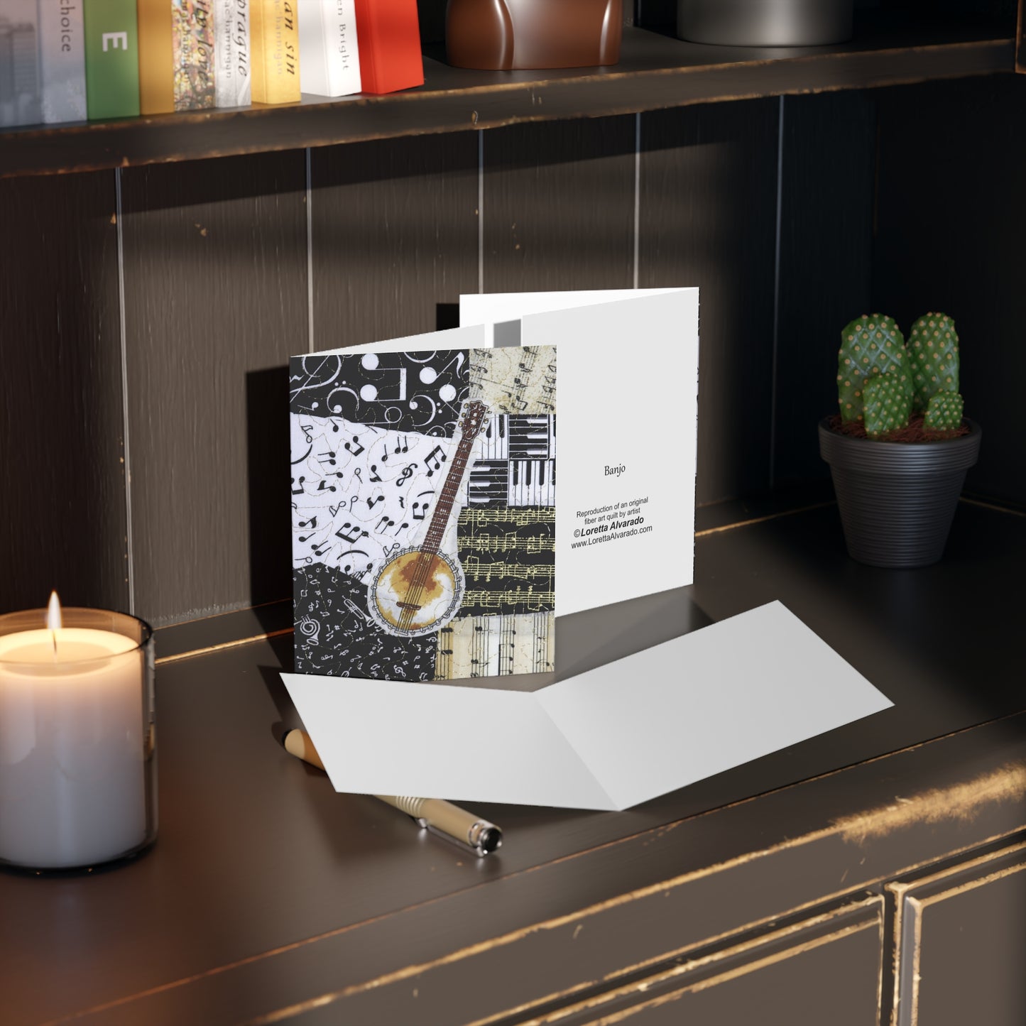 Greeting card with banjo musical design on a dark surface with a candle and plant.