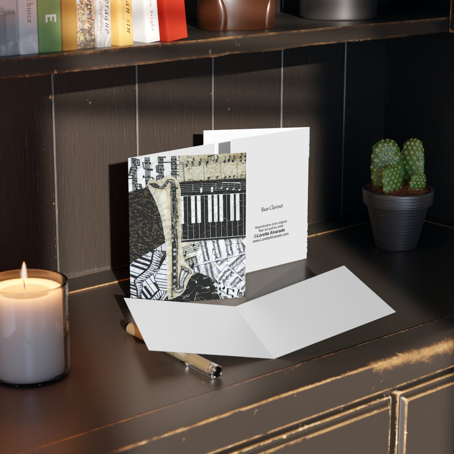 Greeting card with bass clarinet design on a desk next to a candle and pen