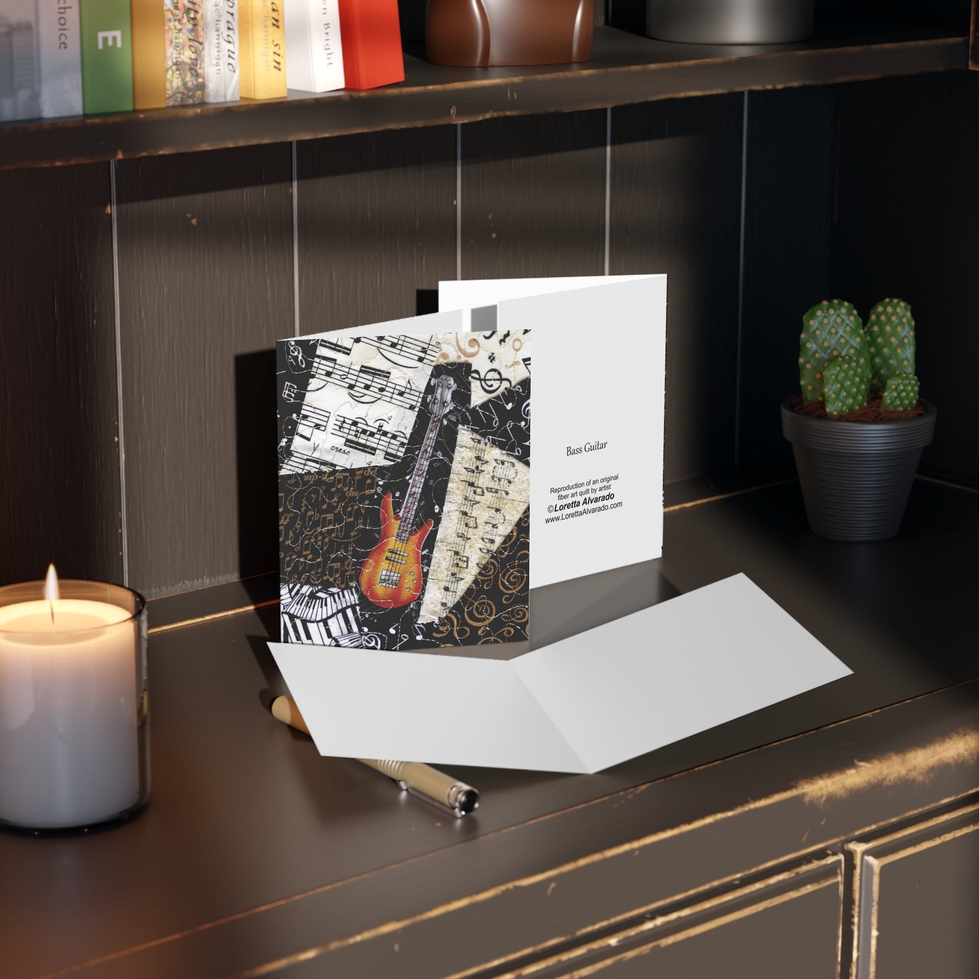 Greeting card with bass guitar design on a desk next to a candle and pen