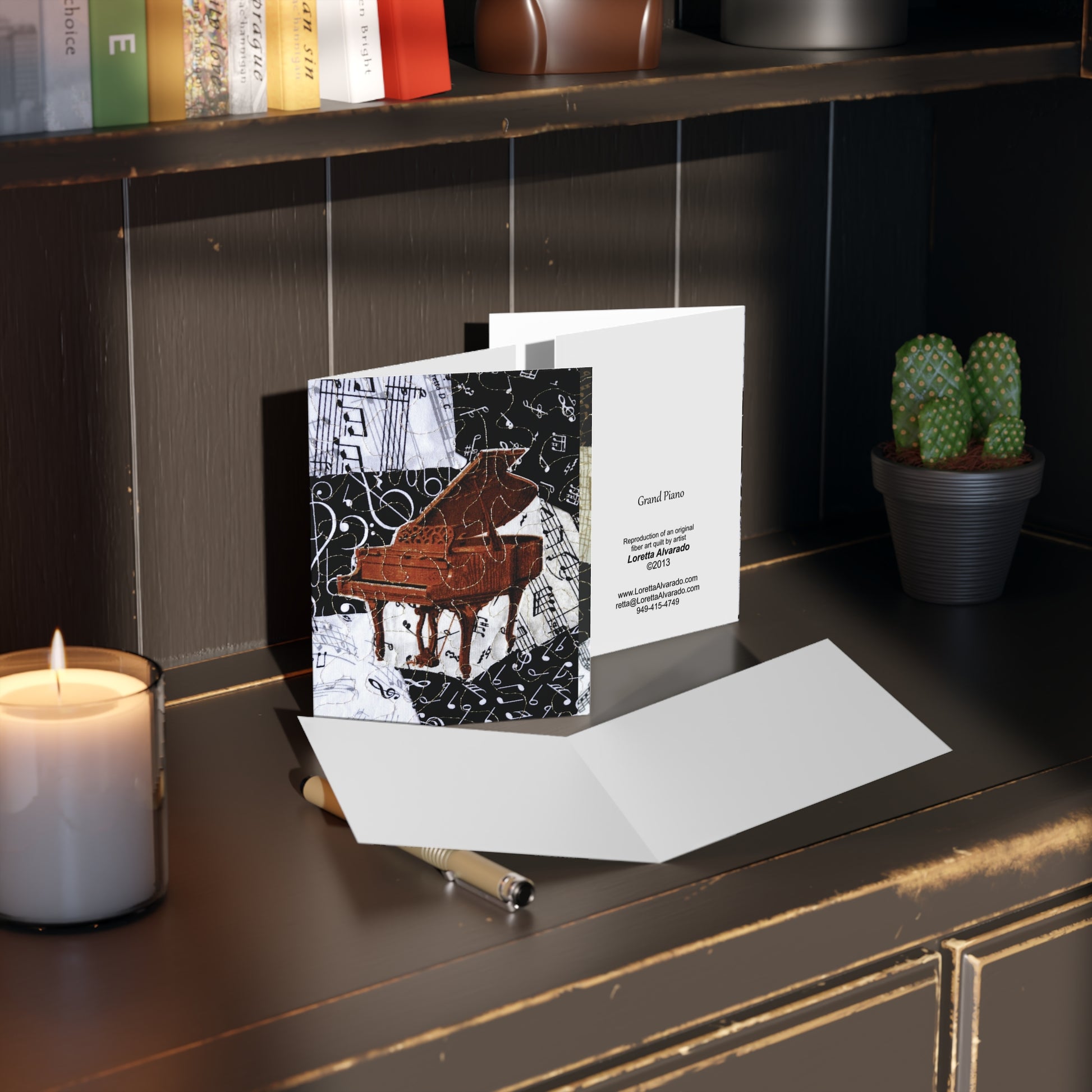 Greeting card with brown grand piano design on a dark surface with a candle and plant.