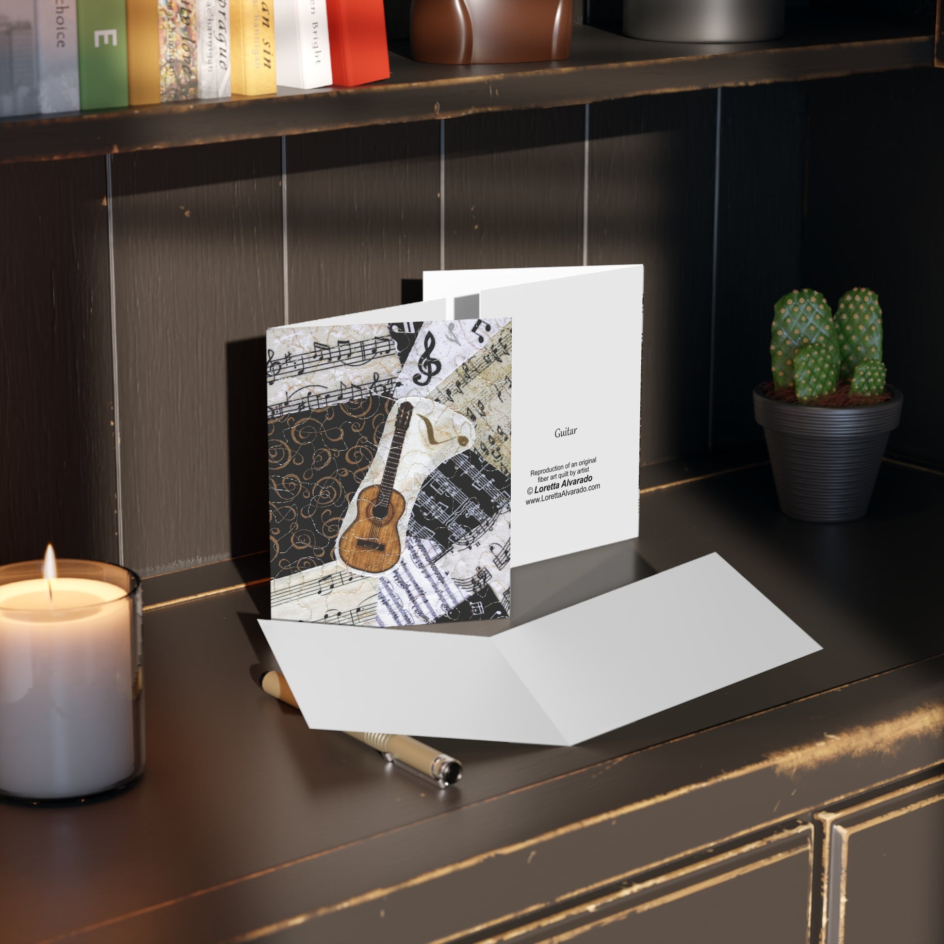 Greeting card with a classical guitar design on a dark surface with a candle and plant