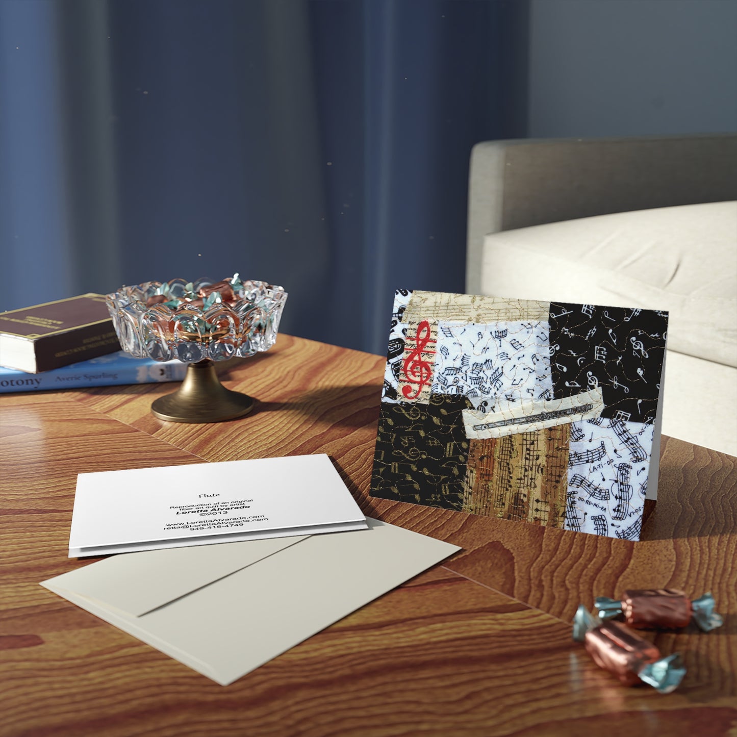 Wooden table with greeting cards with music-themed flute design, envelopes, and decorative items against a blue wall.